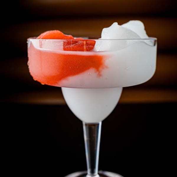 A Retreats New Orleans Style Daiquiri, half strawberry red and half white, in a margarita glass.