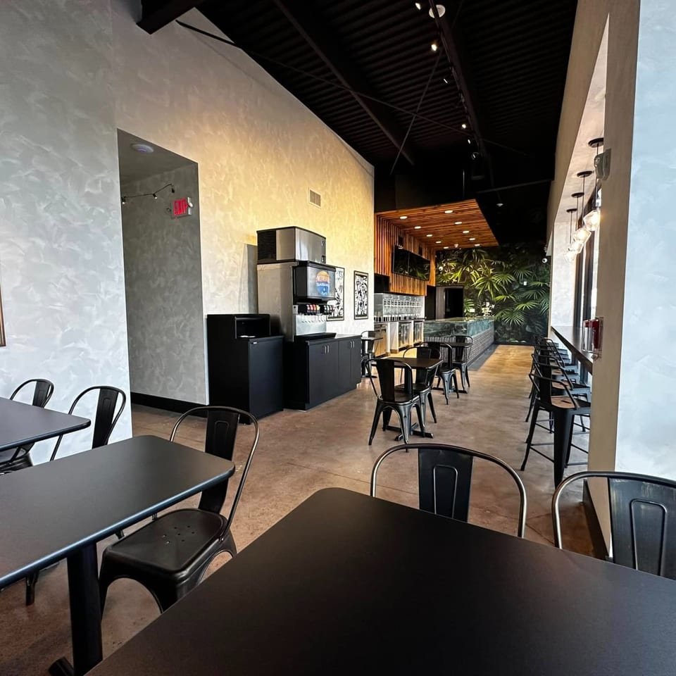 Interior of Retreats New Orleans Style Daiquiris & Eats, featuring black tables and chairs, and a daiquiri bar.